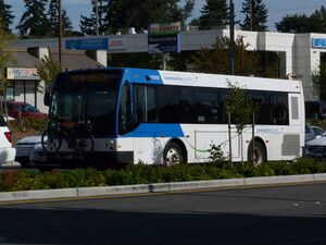 Community Transit no 43609 at Lynnwood City Center Station. The bus is mostly white, with some blue around the front of the bus. The photo is shot from the driver's front side.